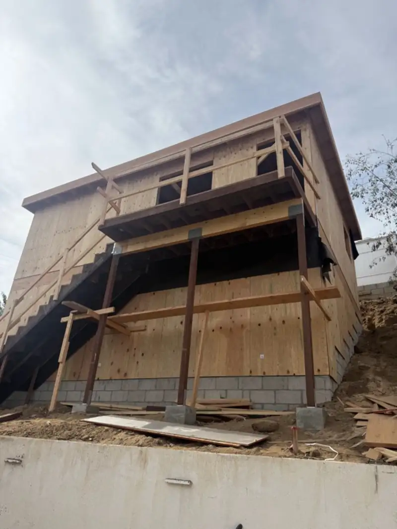 Hillside addition framed and braced above a retaining wall