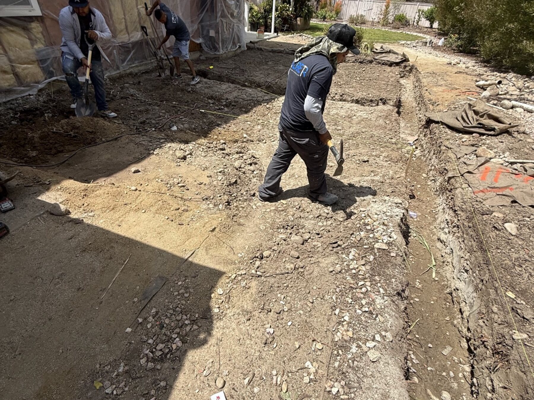 Three BMA crew members trenching beside a house wrapped for work